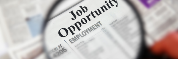 Magnifying glass showing the text 'job opportunity' on a newspaper