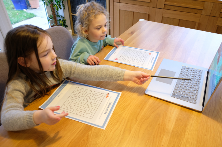 Children doing worksheets looking at laptop